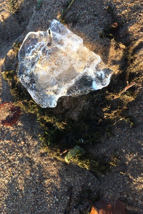 jääpala kimaltelee auringossa hiekkarannalla.
