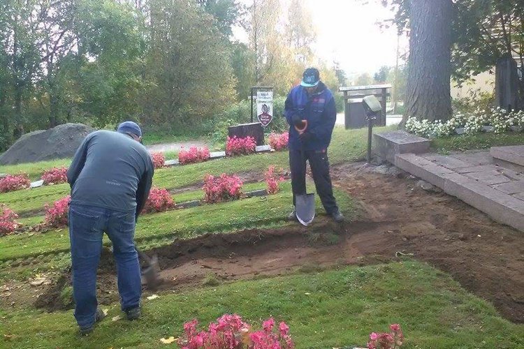 Kaksi työntekijää lapioivat hautausmaalla kesällä.