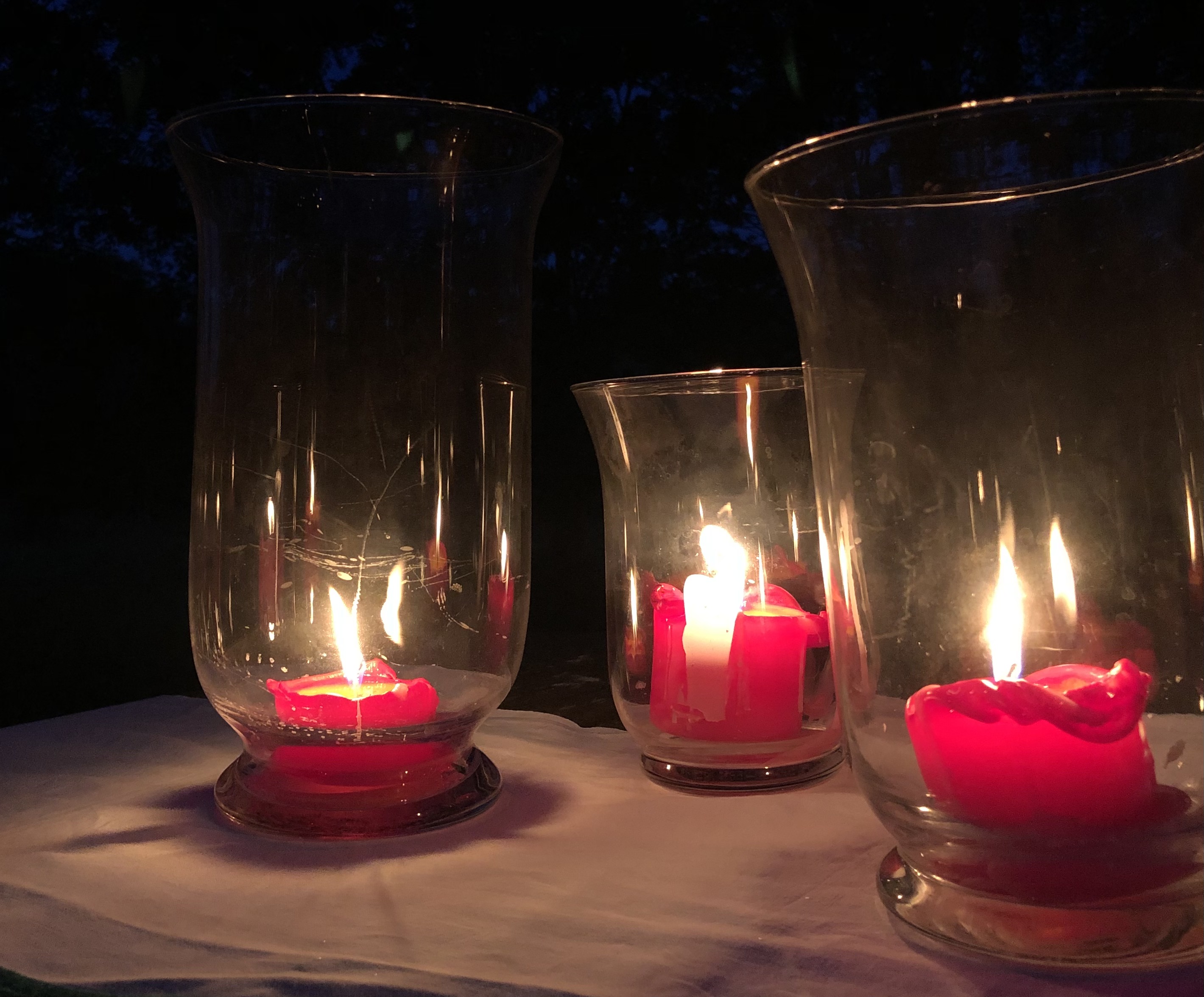 Kolme kynttilää palaa tunnelmallisesti lasilyhdyissään.
